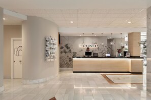 Un espace d’accueil moderne doté d’un comptoir d’accueil incurvé, d’un écran numérique et d’un présentoir mural pour les produits.