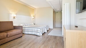 A modern hotel room with a large bed, a sofa, and a wooden desk. - Hotel Best Da Vinci  (Salou)