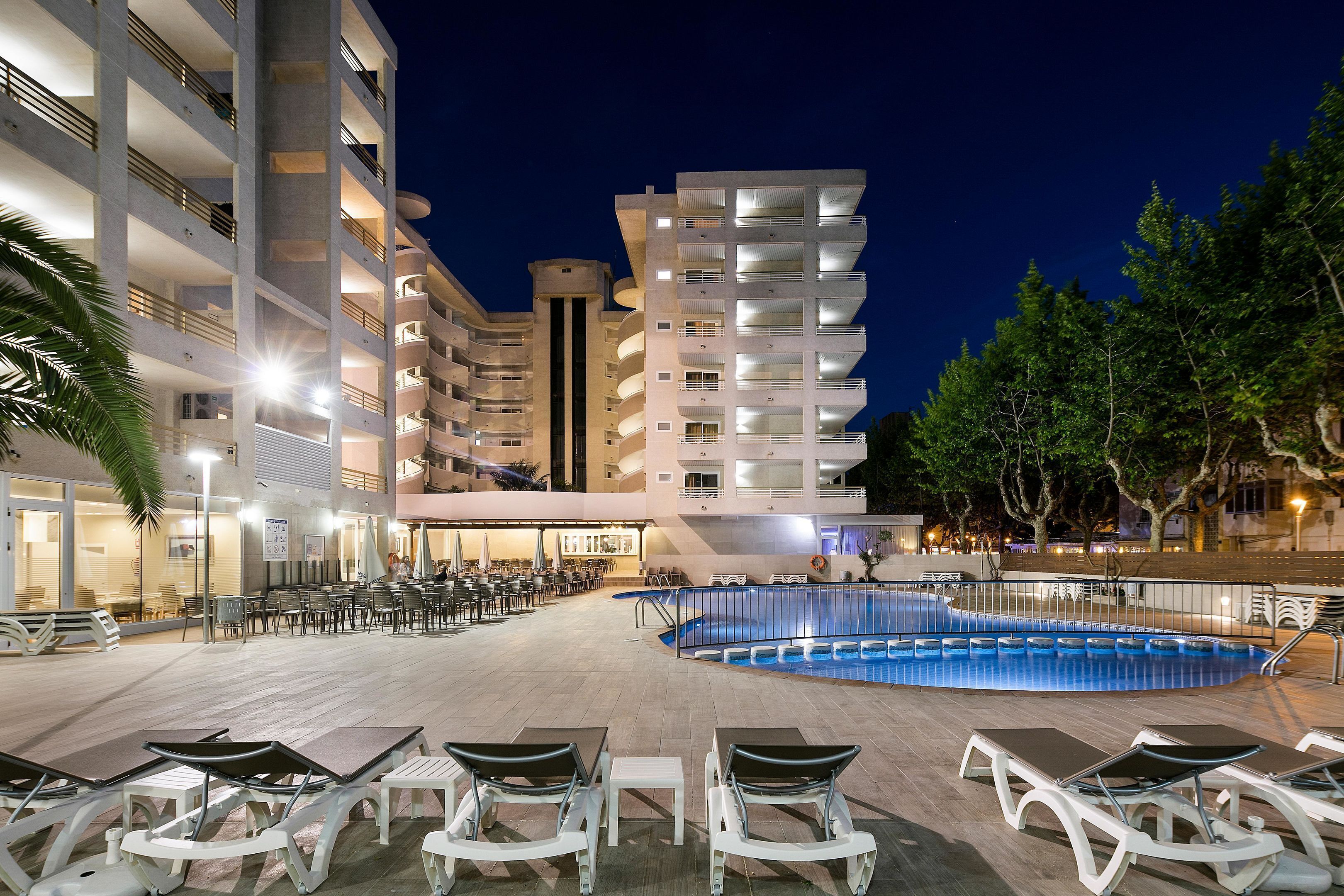 A hotel with multiple floors, outdoor pool, and lounge area with sunbeds.