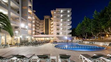 A hotel with multiple floors, outdoor pool, and lounge area with sunbeds.