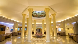 A spacious lobby with high ceilings, large columns, and a central fountain. - Medina Belisaire &Thalasso (Hammamet)