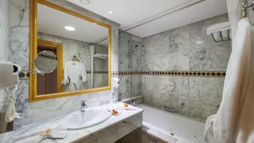 Ein Badezimmer mit Marmorwaschbecken, einem großen Spiegel, einer Badewanne und einer Dusche.
