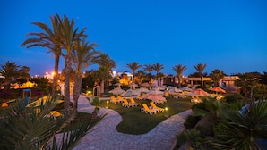 A resort with a pool area, palm trees, and lounge chairs. - Medina Belisaire &Thalasso (Hammamet)