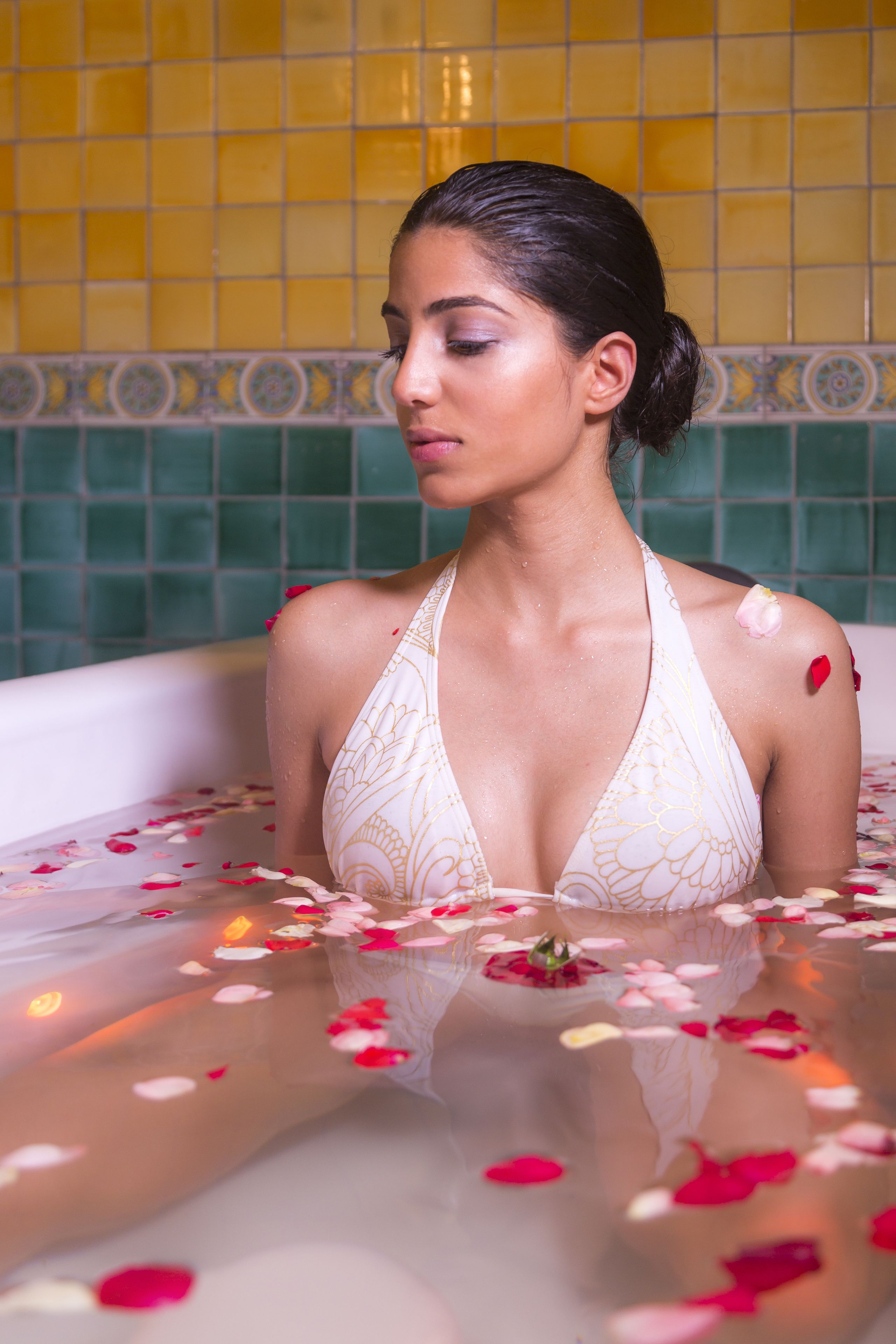 Una mujer en una bañera llena de pétalos de rosa.