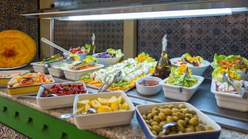 Un bufé con diversos platos, incluidas ensaladas, frutas y verduras.