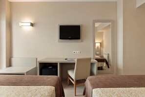 Una habitación de hotel con dos camas, un escritorio, una silla, un televisor y un espejo.
