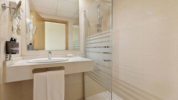 A modern bathroom with a glass shower enclosure, a sink with a mirror, and a towel rack.