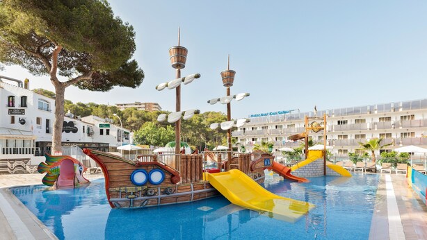 A swimming pool with a pirate ship play area, a slide, and a view of hotel buildings in the background. - Hotel Best Cap Salou (Salou)