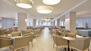 A spacious indoor area with multiple seating arrangements, including chairs and tables, and a modern ceiling design with circular light fixtures. - Hotel Best Cap Salou (Salou)