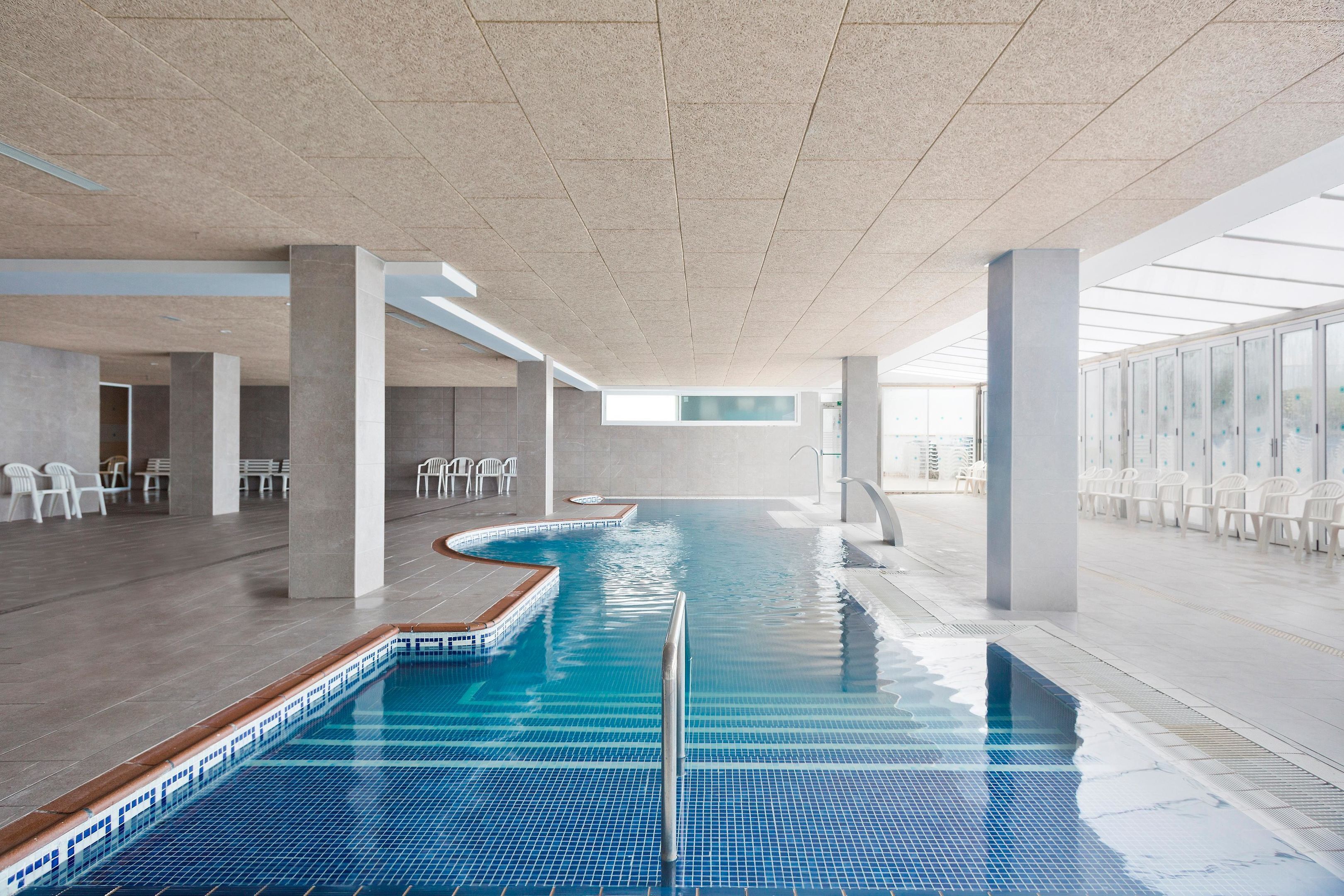 Una piscina cubierta, una piscina al aire libre, tumbonas