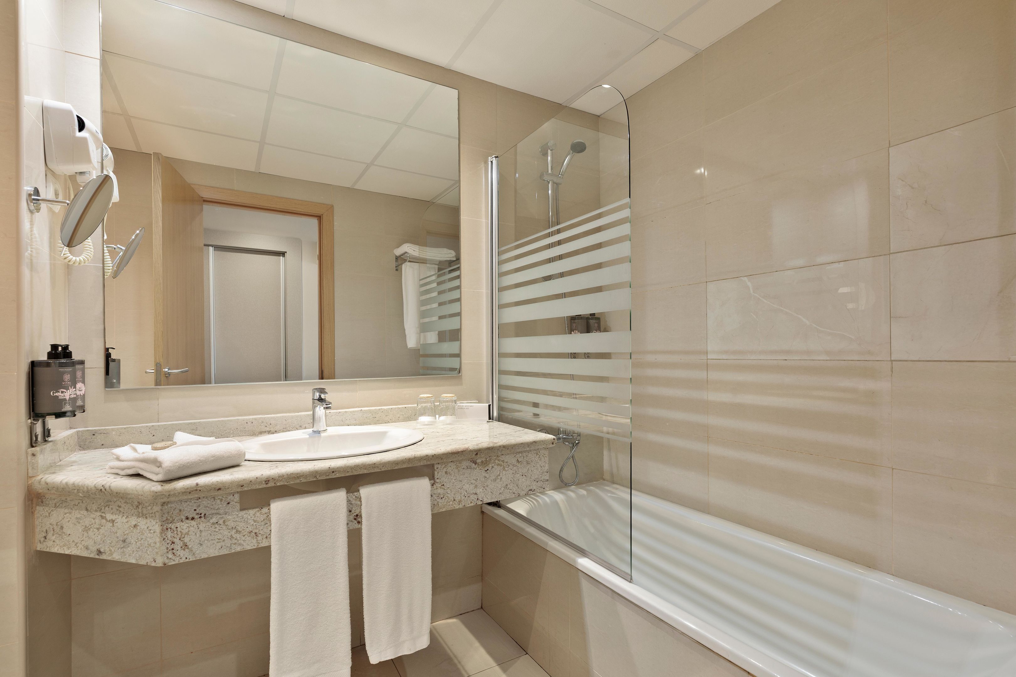 Un baño moderno con lavabo, espejo y ducha.