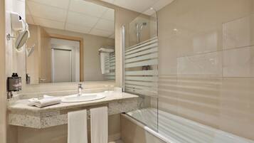 Un baño moderno con lavabo, espejo y ducha.