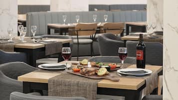 Un interior de restaurante con paredes de mármol, mesas de madera, sillas acolchadas e iluminación colgante.