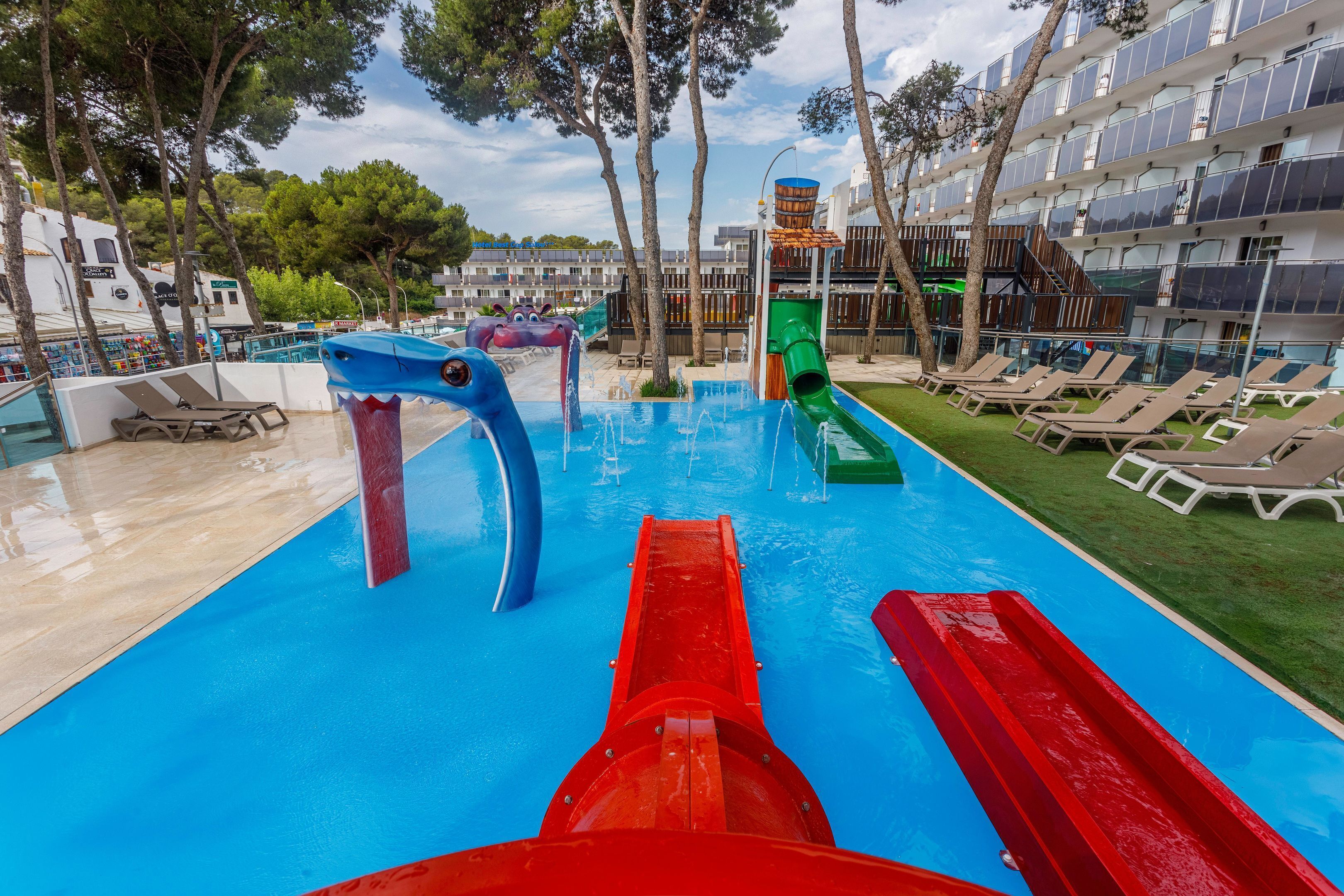 A pool area with slides, lounge chairs, and a building with balconies.