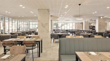A spacious restaurant with high ceilings, marble columns, and a variety of seating options including booths and tables.