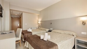 Habitación de hotel con dos camas, un escritorio, una silla y un televisor.