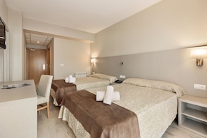 A hotel room with two beds, a desk, a chair, and a TV.