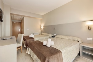 A hotel room with two beds, a desk, a chair, and a TV.