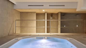 A spa area with a hot tub, a shower, and a glass-enclosed sauna.