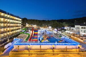 Un parc aquatique avec des toboggans et des piscines, entouré d’immeubles.