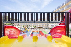 Parque acuático con múltiples toboganes y una vista de un hotel al fondo.