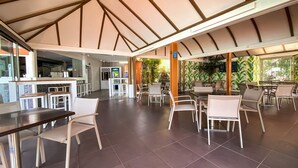A spacious indoor area with a high ceiling, multiple seating arrangements, and a visible kitchen area. - Bungalows Cordial Sandy Golf (San Bartolomé de Tirajana)