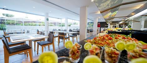 A modern dining area with a buffet, tables, and chairs.