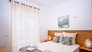 A neatly made bed with pillows, a bedside lamp, and a wall-mounted picture. - Jardins Vale de Parra (Albufeira)