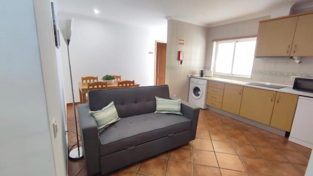 A compact living space with a sofa, a washing machine, and a kitchenette.