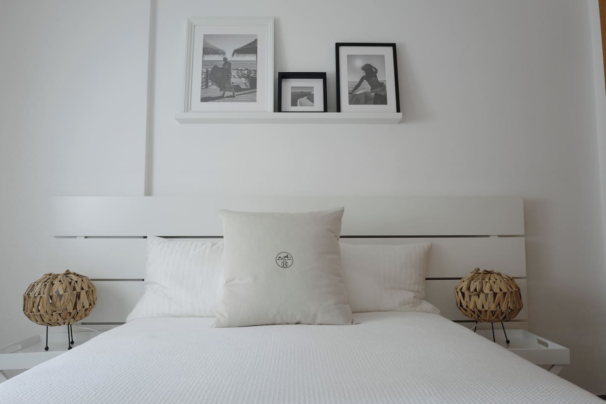 A neatly arranged bedroom with a large bed, two bedside tables, and three framed pictures on the wall.