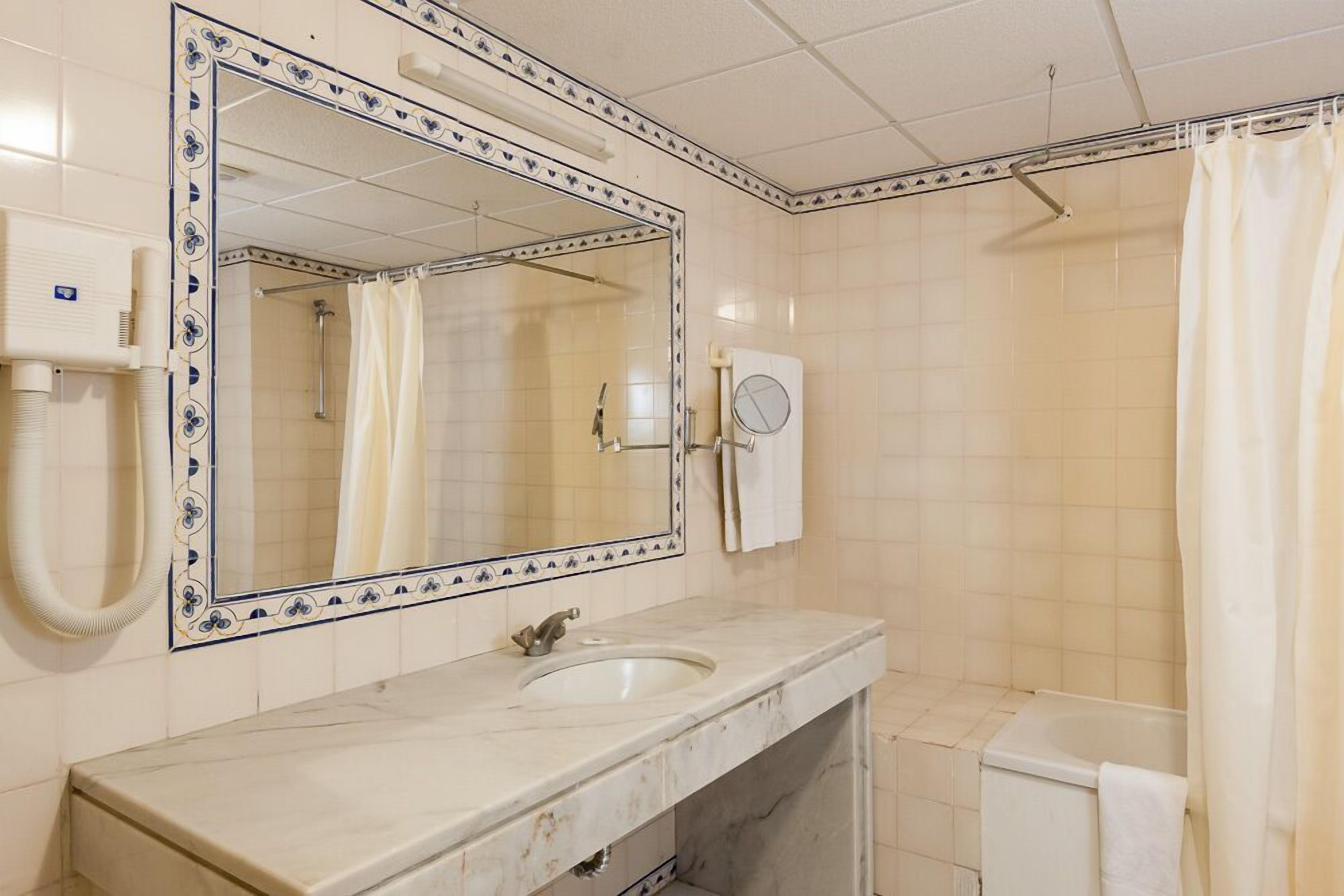 Une salle de bain avec un grand miroir, un lavabo, une douche et des toilettes.
