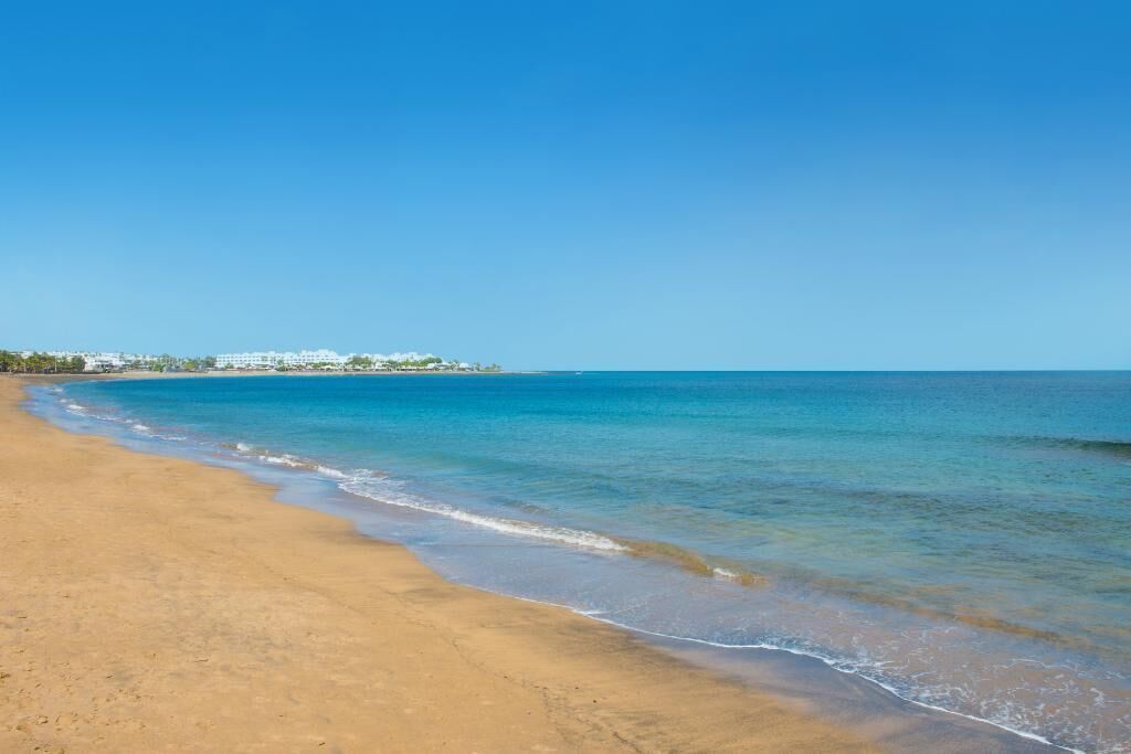 A beach with clear blue water and a sandy shore.