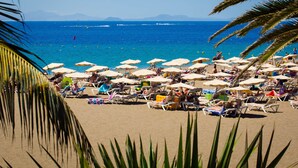 Una playa con numerosos sombrillas y sillas de playa, ofreciendo sombra y asientos para los visitantes.