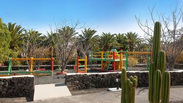 Explore the outdoor play area with a climbing frame and slide, surrounded by palm trees and cacti.