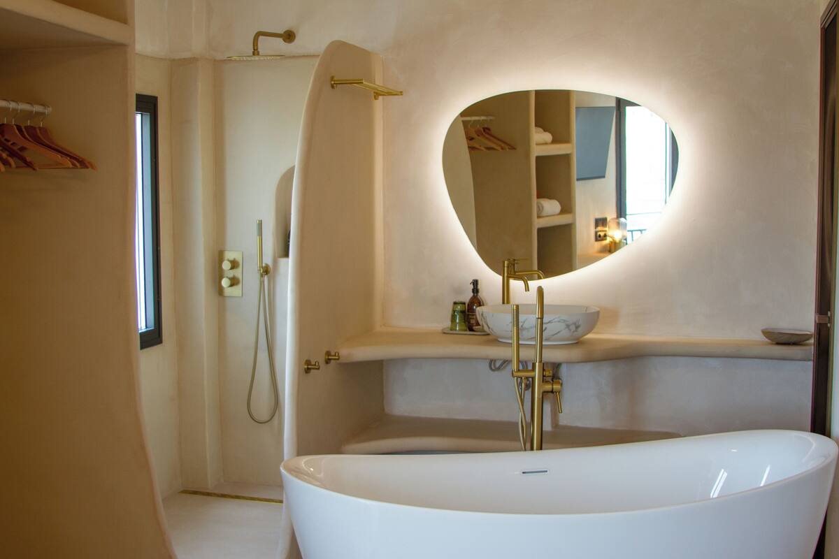 Un baño moderno con una bañera independiente, una ducha a ras de suelo y un lavabo con un espejo grande.