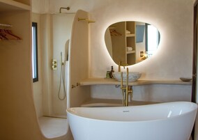 Un baño moderno con una bañera independiente, una ducha a ras de suelo y un lavabo con un espejo grande.