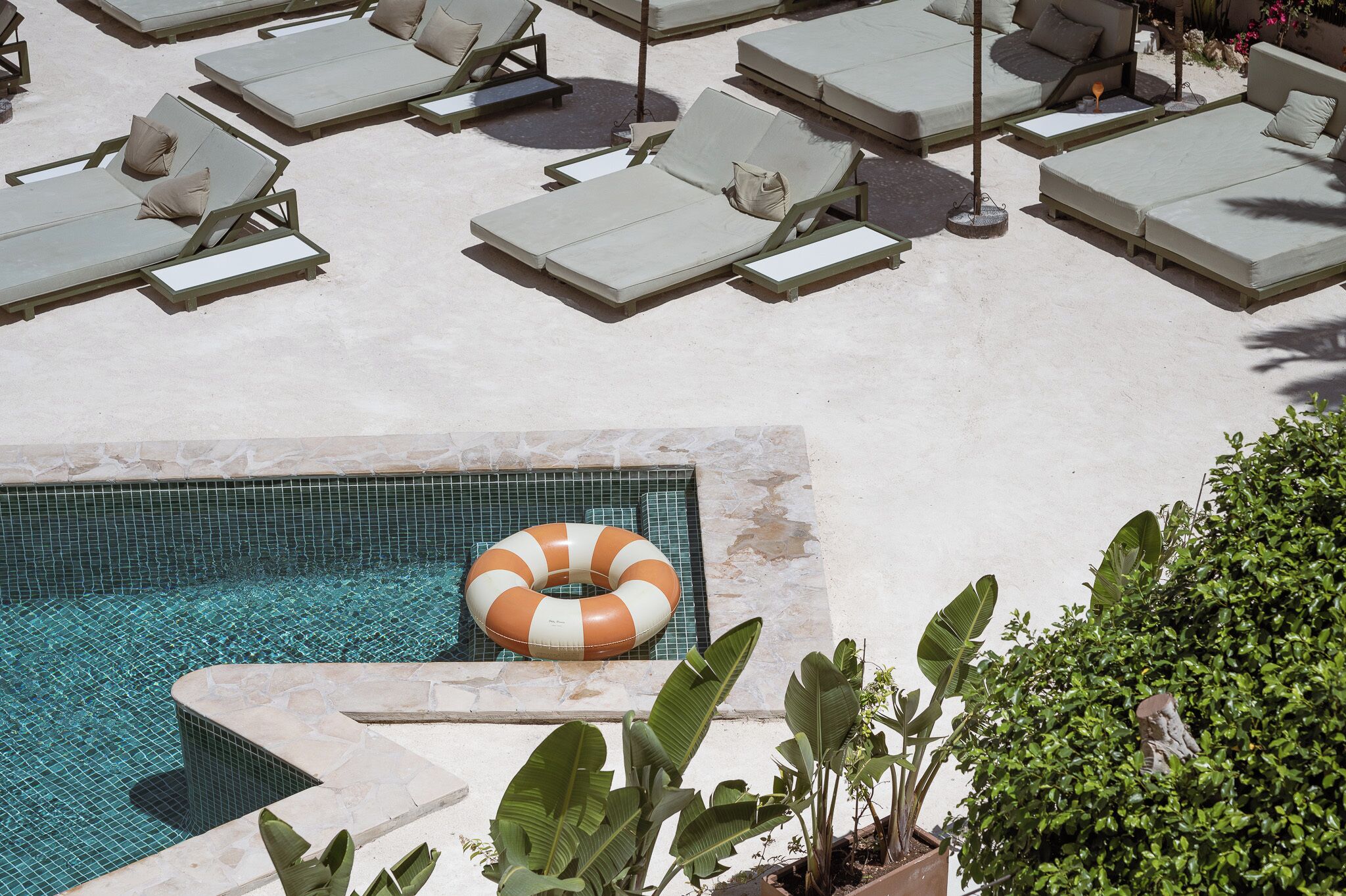 Zona de piscina con varios sillones de sol y un flotador.