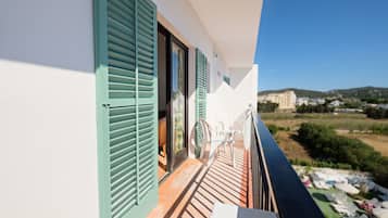 Een balkon met uitzicht op een strand en gebouwen in de verte.