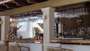 Un área de bar al aire libre con sillas de madera, una barra y un techo de azulejos.