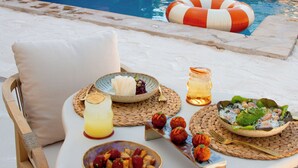 A poolside dining setup with a table, cushions, and various dishes. - Hotel Galfi - Boutique & Adults Only (Sant Antoni de Portmany)