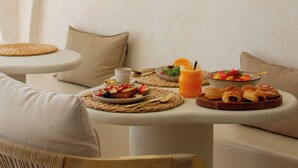 A dining area with a round table set for breakfast, including fruits, pastries, and a glass of orange juice. - Hotel Galfi - Boutique & Adults Only (Sant Antoni de Portmany)