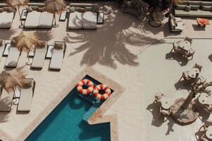 Zona junto a la piscina con tumbonas, una piscina pequeña y mobiliario de exterior.