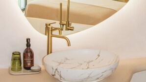 A circular mirror reflecting a bedroom with a bed, a gold faucet, and a marble basin. - Hotel Galfi - Boutique & Adults Only (Sant Antoni de Portmany)