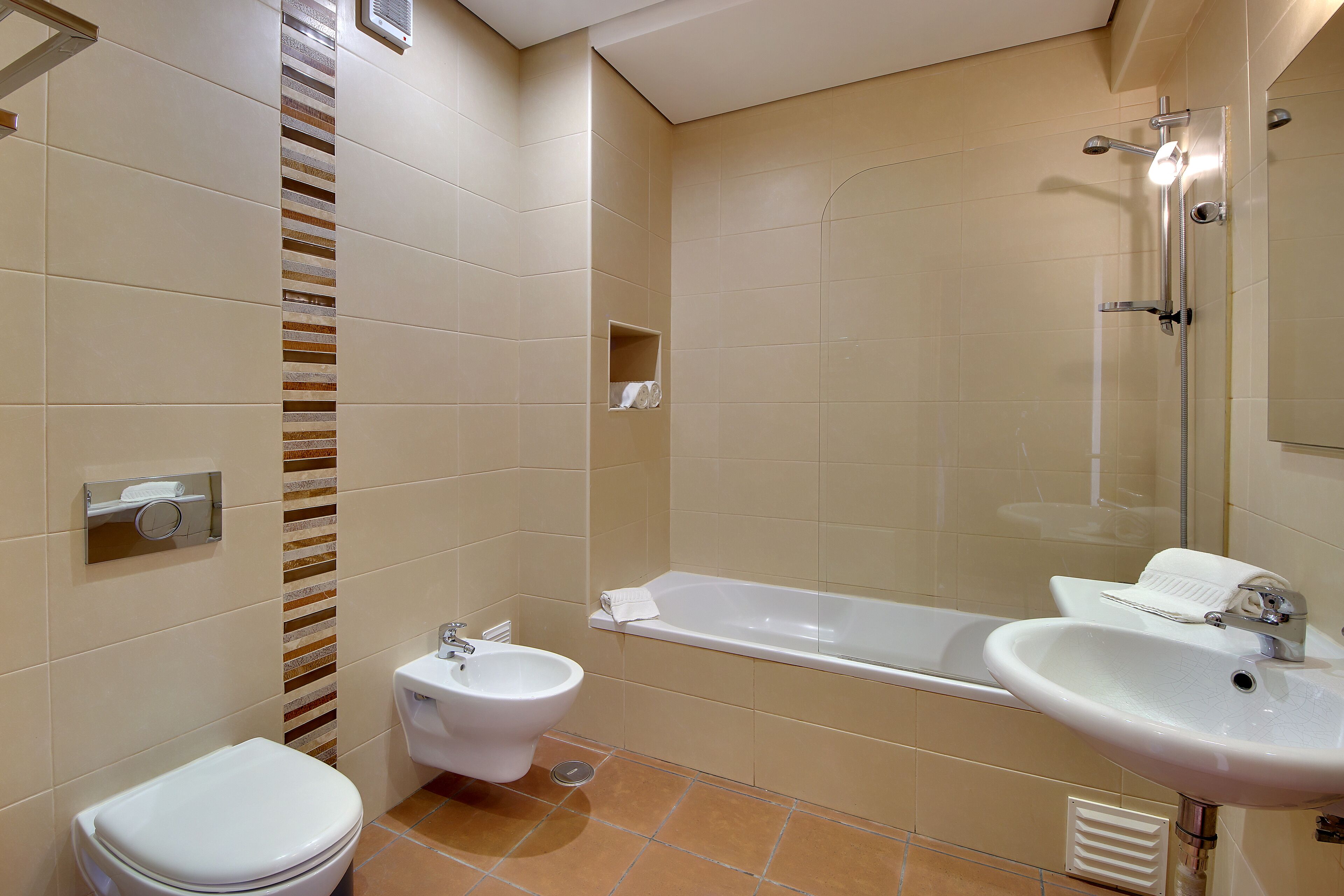 A modern bathroom with a toilet, bidet, bathtub, and sink.