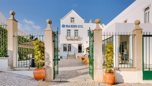A hotel entrance with a gated driveway, potted plants, and outdoor seating. - Hotel Vila Recife (Albufeira)