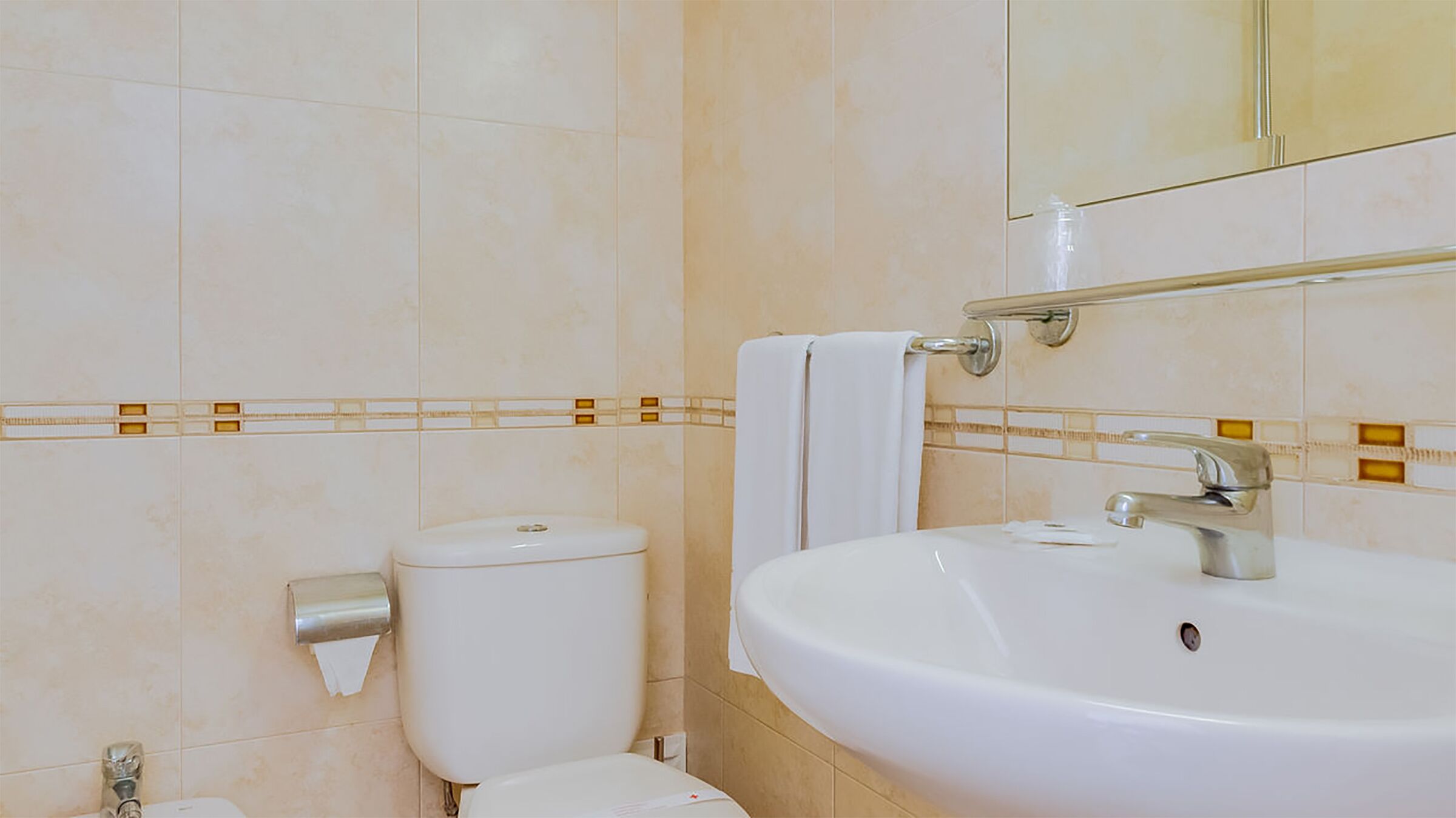 Un baño con inodoro, lavamanos y espejo.