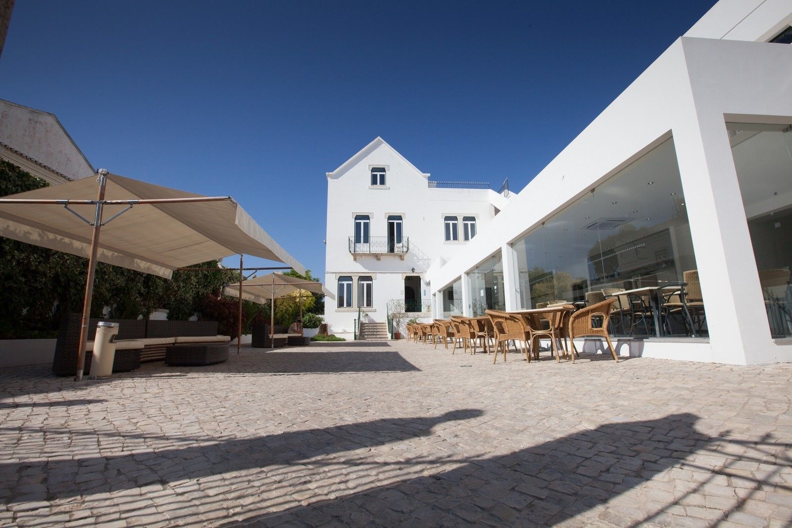 Un patio con mobiliario exterior y un edificio con ventanas amplias.