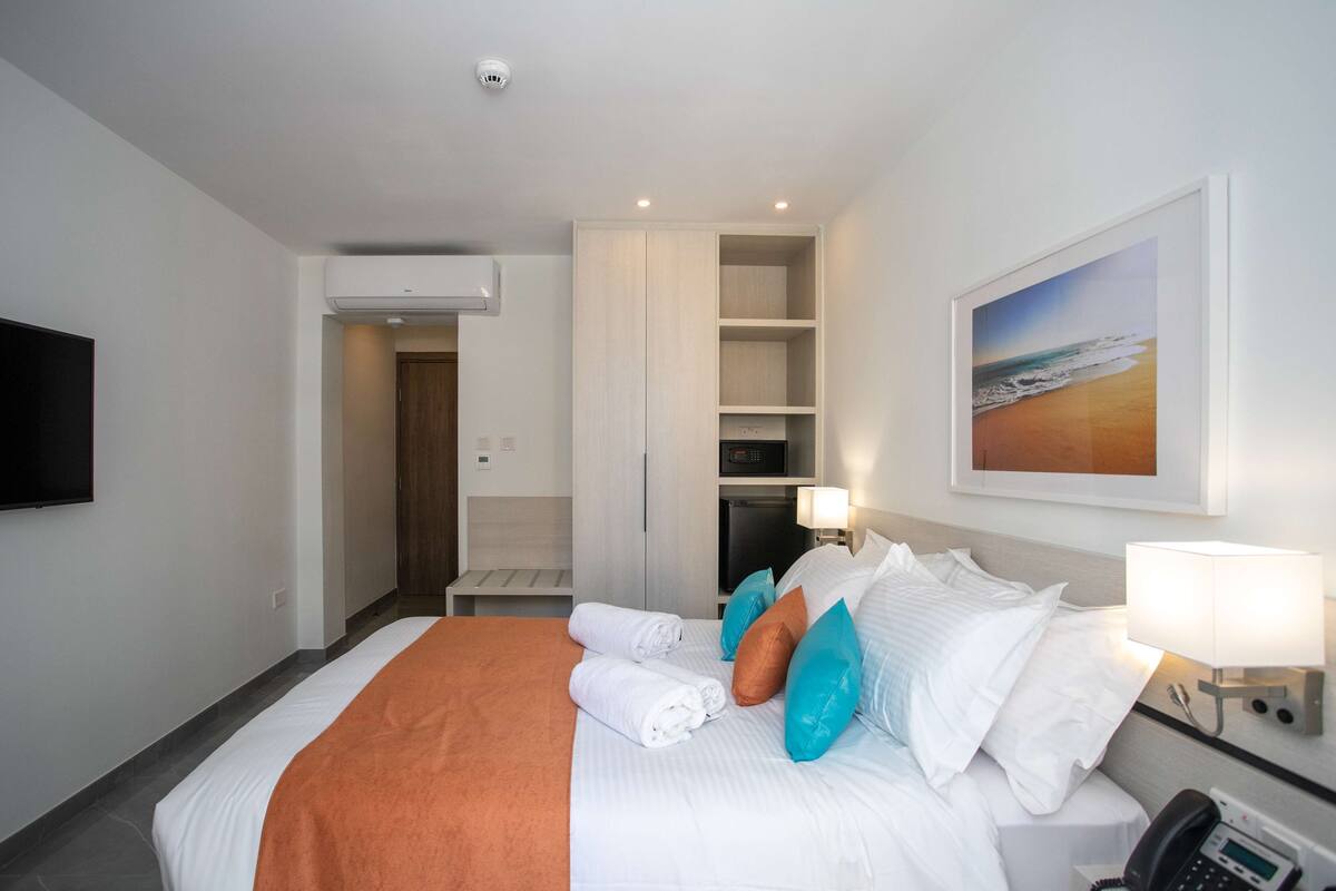 Ein Hotelzimmer mit Bett, Fernseher, Schreibtisch und Kleiderschrank.