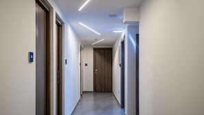 A modern hallway with a wooden door at the end, recessed lighting, and a clean, tiled floor. - Best Western Plus Larco Hotel (Larnaca)