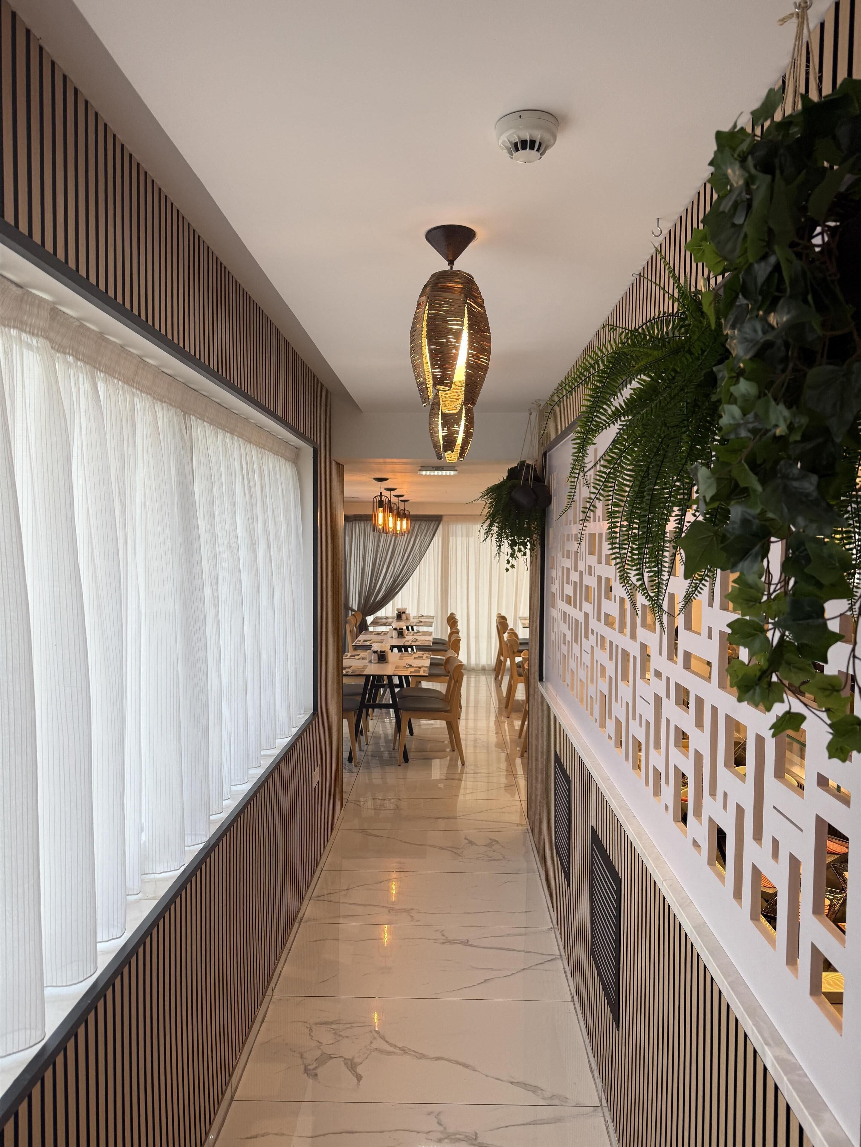 A corridor with a dining area, marble flooring, and a decorative ceiling light.